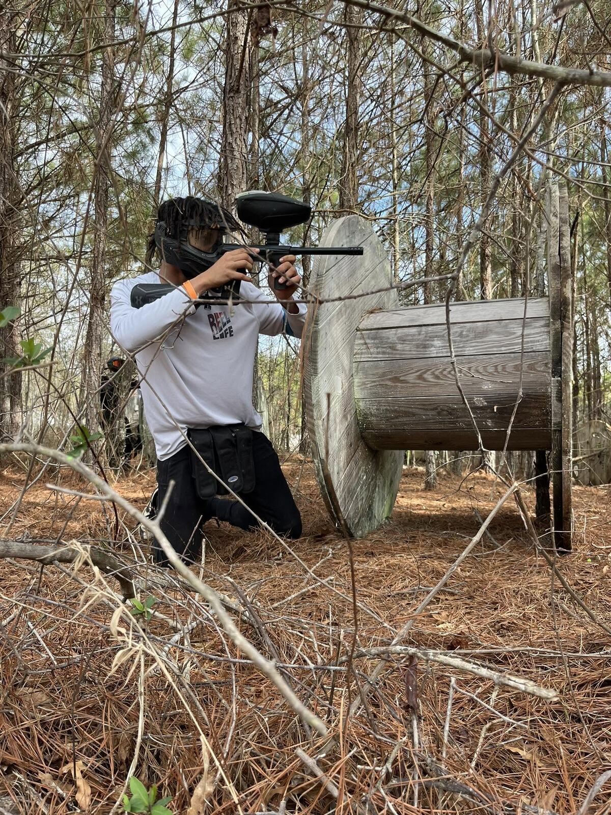 Rugged outdoor paintball field surrounded by pine trees